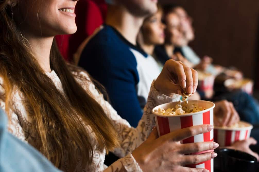 A smiling woman eating popcorn at a movie theater