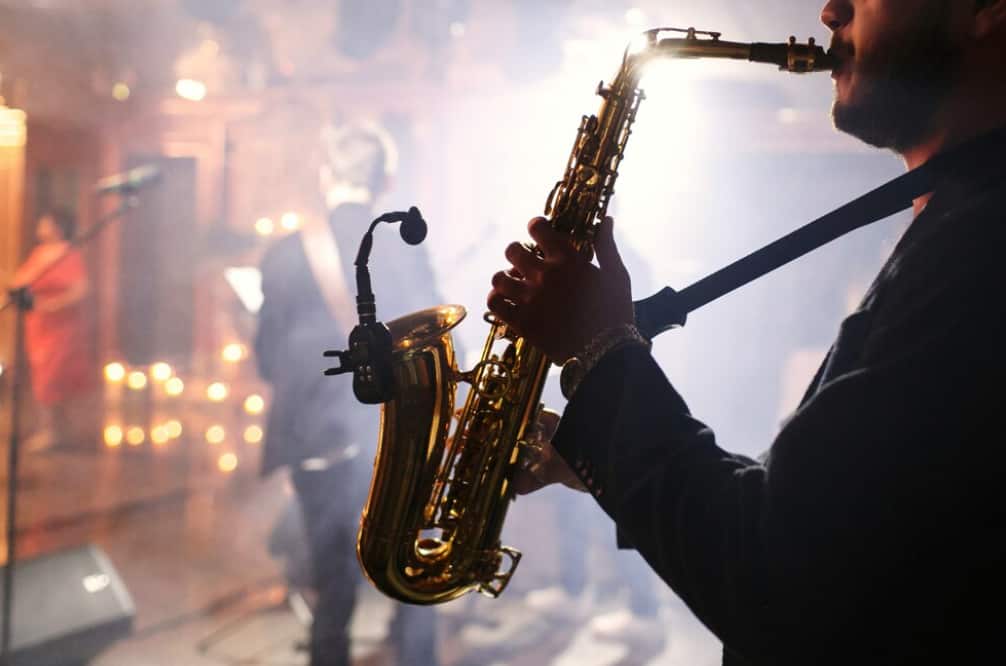 A man playing the saxophone on a stage with dim lighting