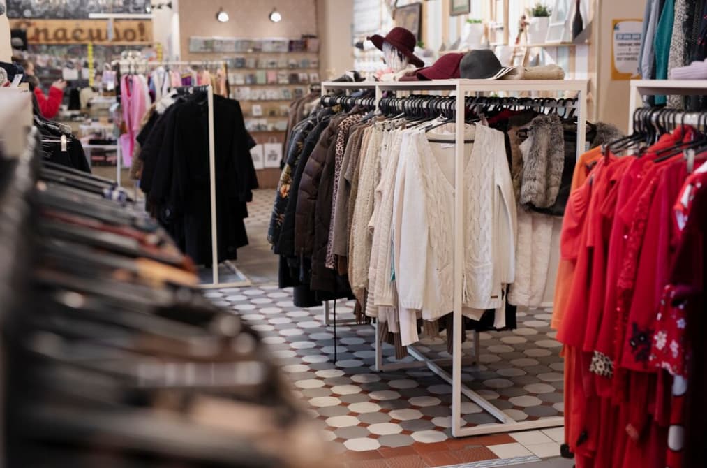 Various clothing items on racks in a well-lit, patterned floor retail store