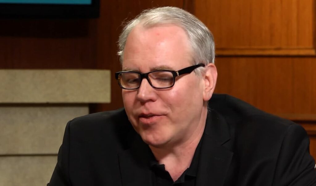 Middle-aged man in glasses speaking during an interview
