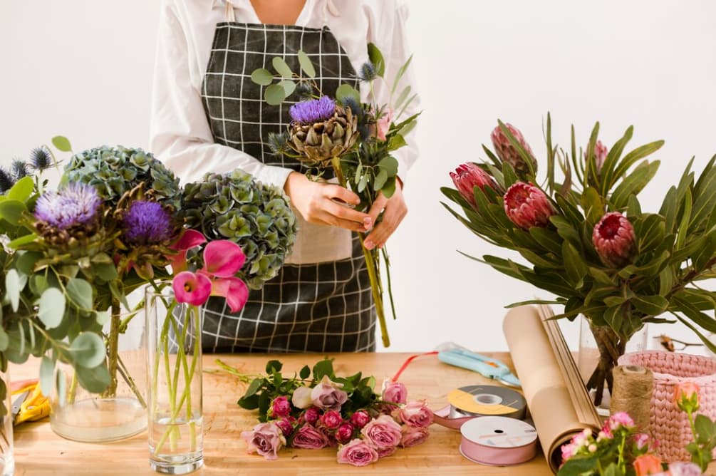 A person prepares a floral arrangement with a variety