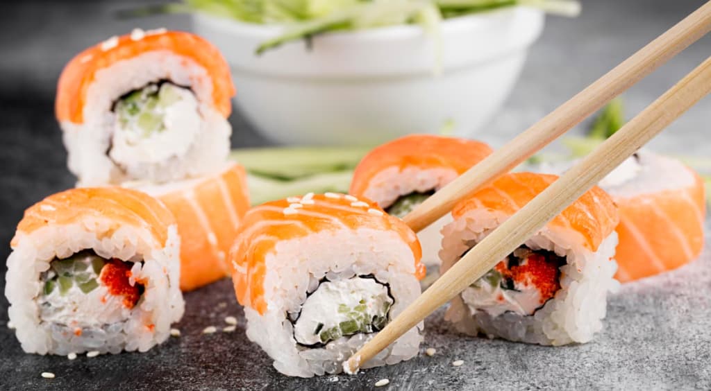 Philadelphia sushi rolls picked up with chopsticks