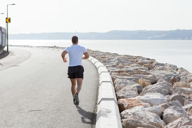 A man runs along the road near the shore