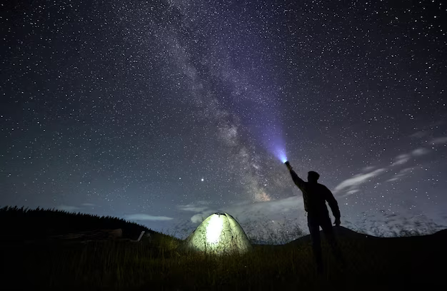 A man shines a flashlight into the sky
