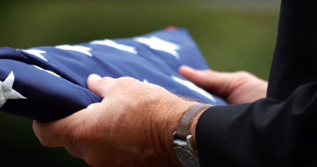 Hands holding a folded American flag, close up view