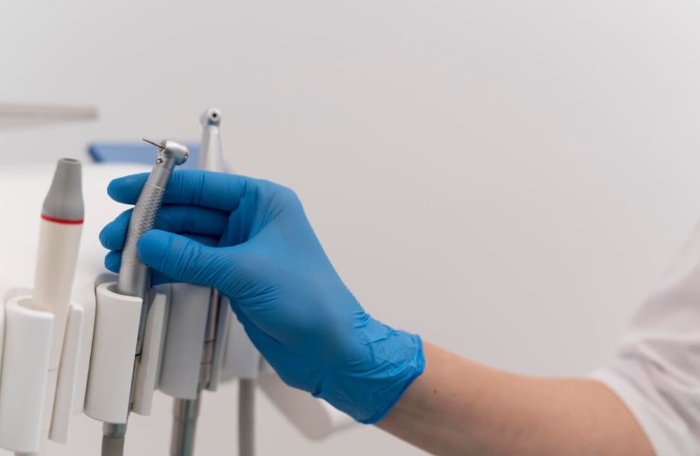 A gloved hand selecting a dental tool from a holder