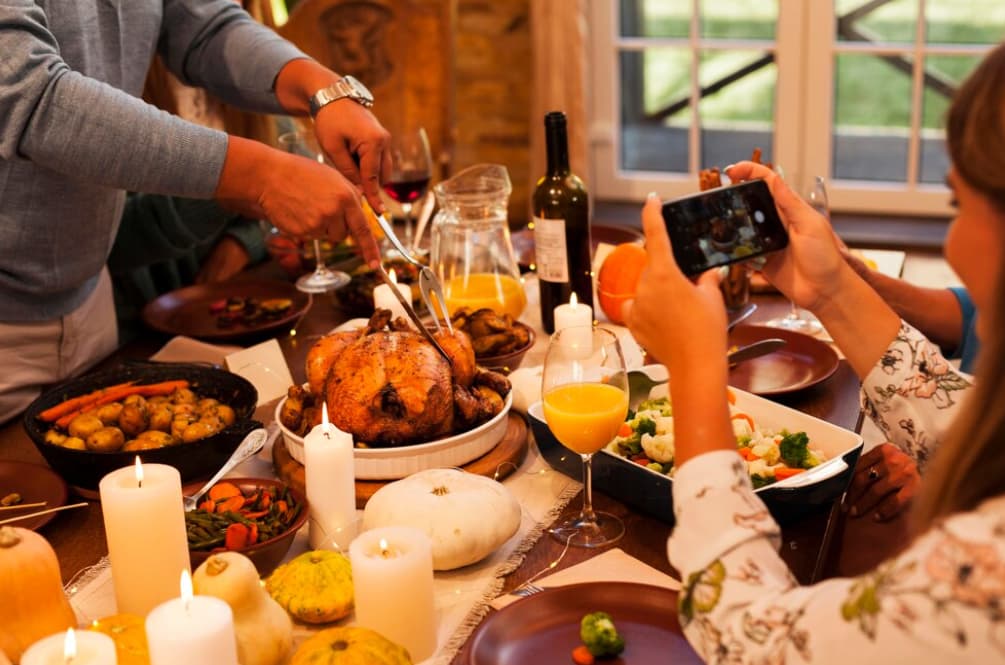 People gathering around a table carving a roasted turkey