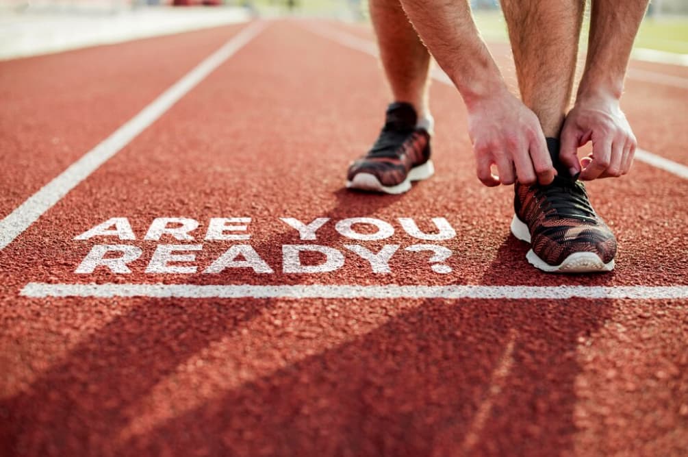 A runner's perspective at the start line with the text "ARE YOU READY?"